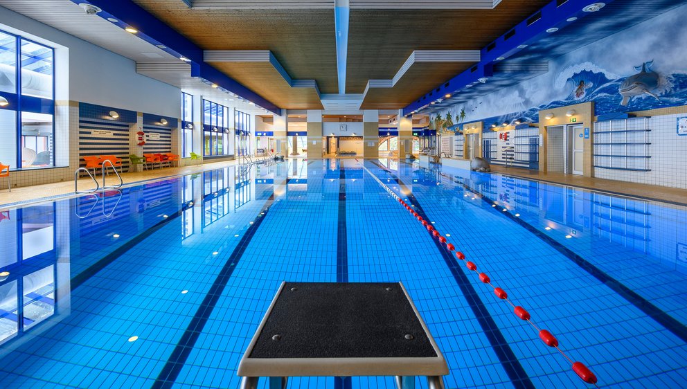 Modernes Hallenbad mit Schwimmbahnen. Das Bild zeigt ein modernes Hallenbad mit einem großen, klaren Schwimmbecken und mehreren Schwimmbahnen – bereit für Sport und Training.