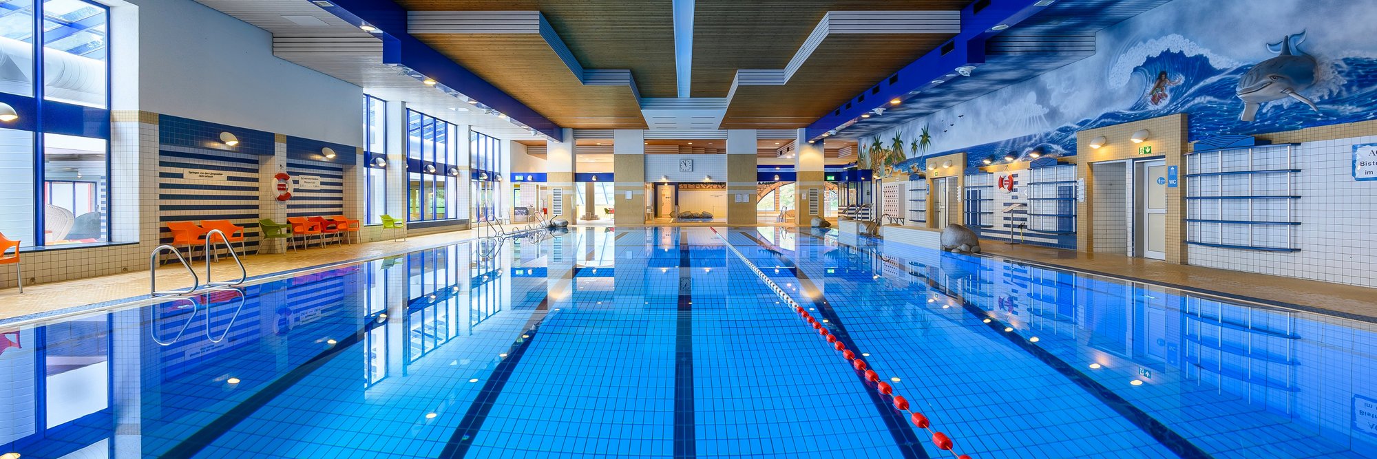 Modernes Hallenbad mit Schwimmbahnen. Das Bild zeigt ein modernes Hallenbad mit einem großen, klaren Schwimmbecken und mehreren Schwimmbahnen – bereit für Sport und Training.