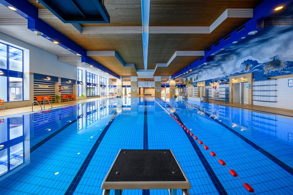 Modernes Hallenbad mit Schwimmbahnen. Das Bild zeigt ein modernes Hallenbad mit einem großen, klaren Schwimmbecken und mehreren Schwimmbahnen – bereit für Sport und Training.