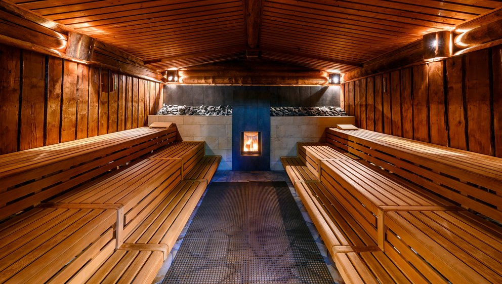 Saunabereich mit Holzbänken und sanfter Beleuchtung. Gemütlicher Sauna-Raum, ausgestattet mit Holzbänken und sanfter Beleuchtung für eine entspannende Atmosphäre.