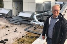 Das Bild zeigt eine Person auf einem Flachdach, umgeben von Lüftungsanlagen und Rohren.