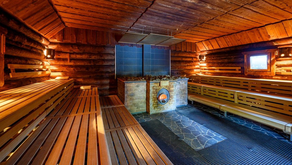 Wellness-Sauna mit sanfter Beleuchtung. Sauna-Raum mit Holzverkleidung, Bänken und sanfter Beleuchtung für Entspannung und Wellness.