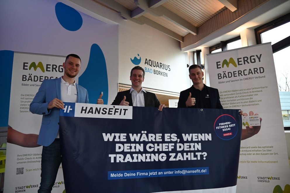 Personen präsentieren Banner mit Trading-Strategie. Das Bild zeigt drei Personen, die zusammen ein Banner halten, auf dem steht: „WIR MACHEN ES, WENN DER CHIEF DIE TRADING-STRATEGIE“.