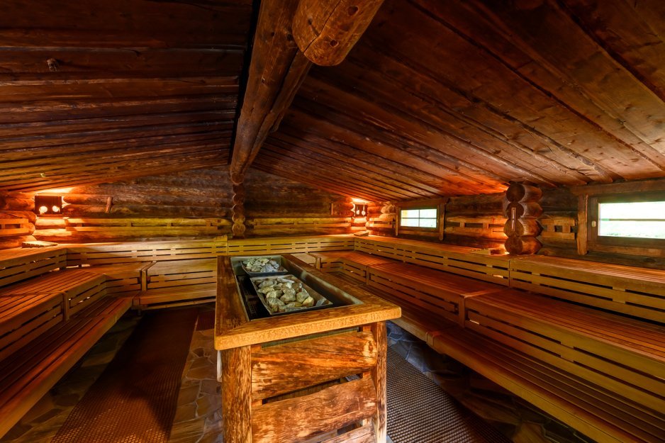 Traditionelle Sauna mit Holzverkleidung. Das Bild zeigt das Innere einer traditionellen Sauna mit Holzverkleidung. Die Bänke sind in mehreren Ebenen angeordnet, und in der Mitte des Raums sind heiße Steine zu sehen.