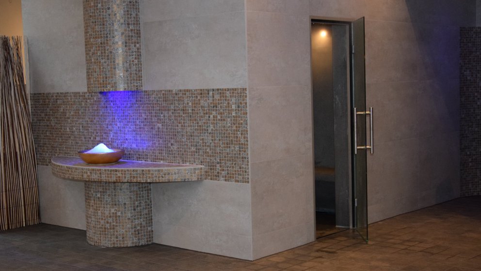 Moderner Wellnessbereich mit Wasserbrunnen. Das Bild zeigt einen modernen Wellnessbereich mit einem eleganten Wasserbrunnen, der sanftes Licht ausstrahlt.