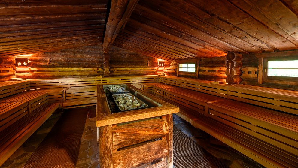 Sauna mit Holzverkleidung und mehreren Ebenen. Das Bild zeigt das Innere einer Sauna, die mit Holz verkleidet ist. Die Bänke sind in mehreren Ebenen angeordnet und bieten Platz für mehrere Personen.