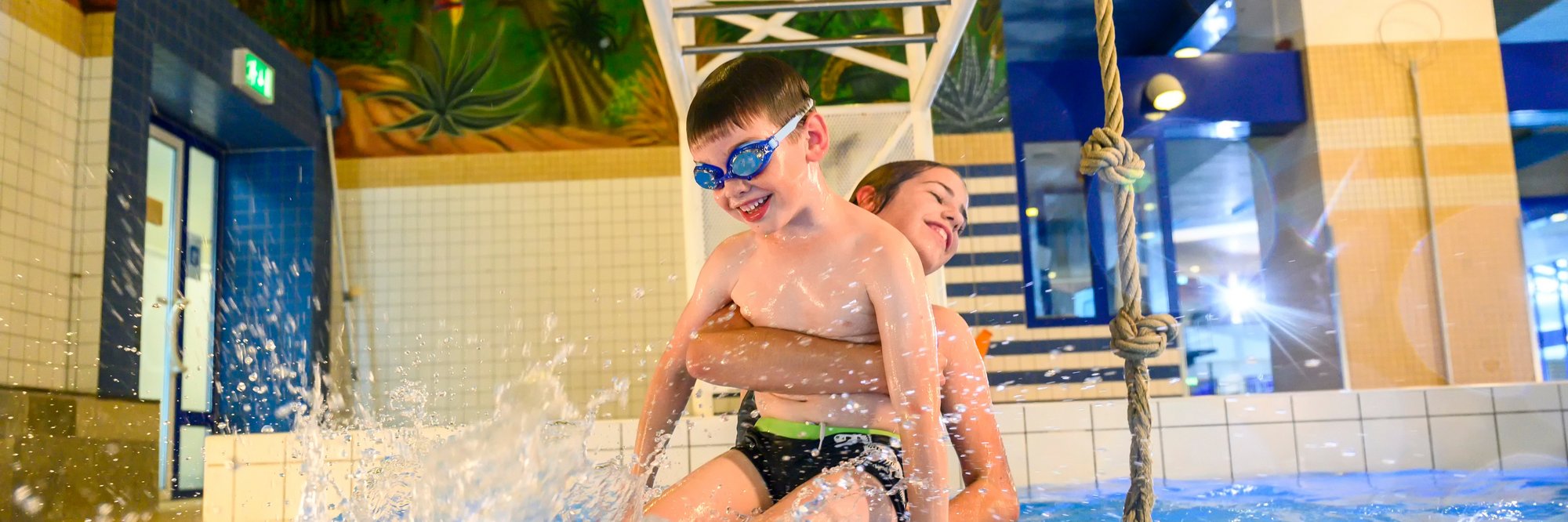 Kinder spielen fröhlich in einem Schwimmbecken.