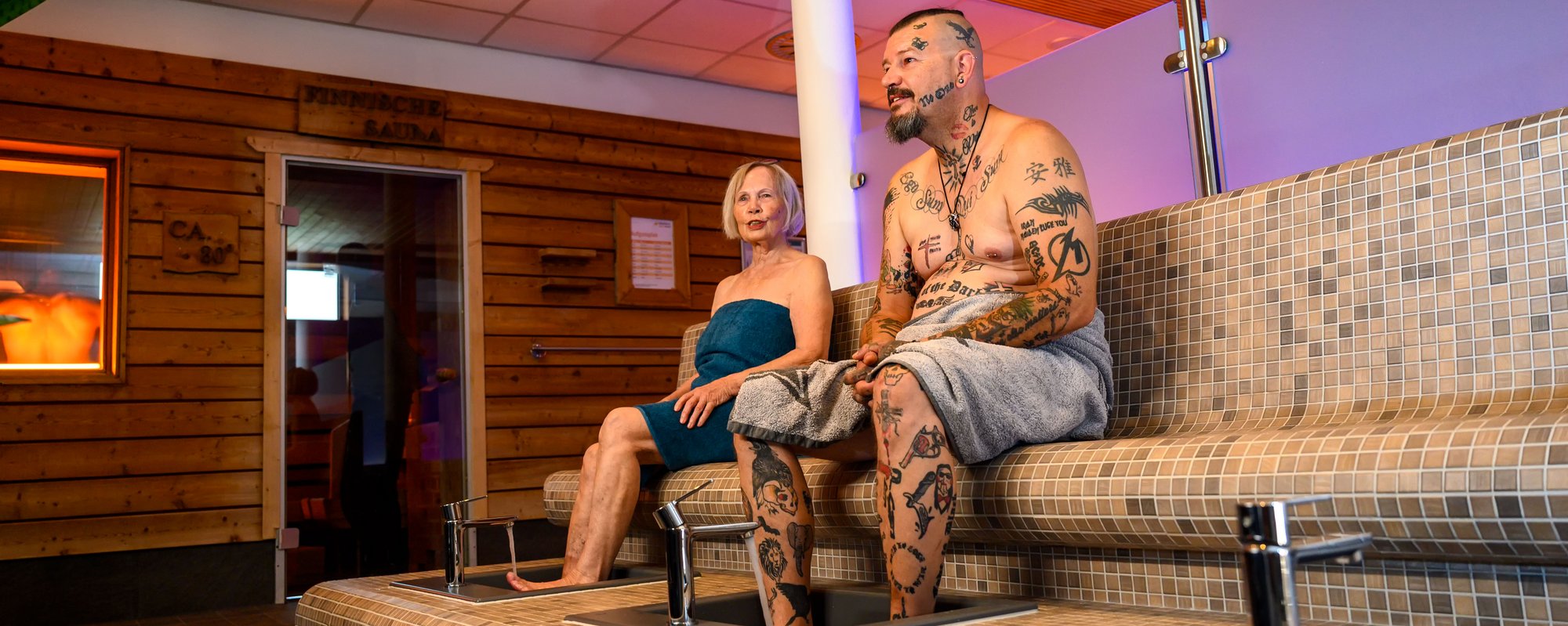 Entspannung in der Sauna auf steinernen Bänken. Das Bild zeigt zwei Personen in einer Sauna, die auf einer steinernen Bank sitzen und sich entspannen. .