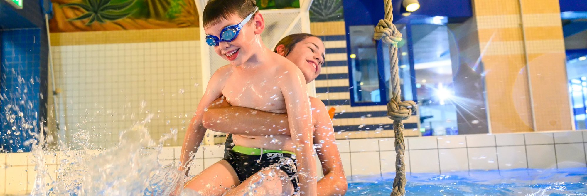 Kinder spielen fröhlich in einem Schwimmbecken.