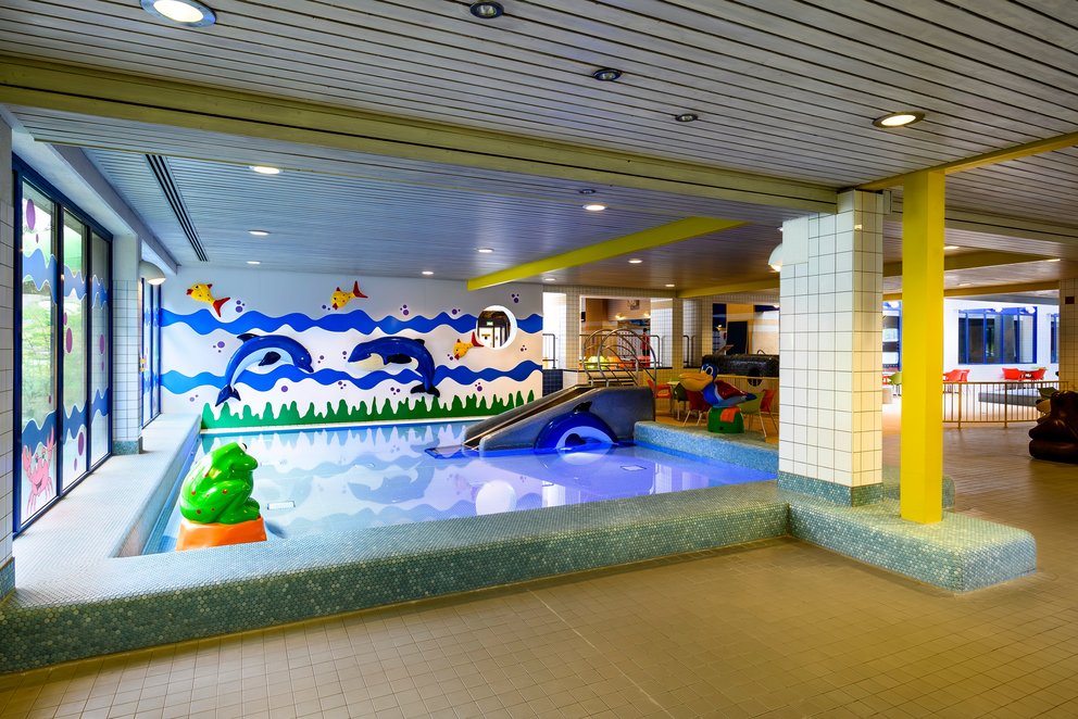speziellen Bereich für Kinder. Großes Hallenbad mit einem bunten Wandgemälde und einem speziellen Bereich für Kinder.